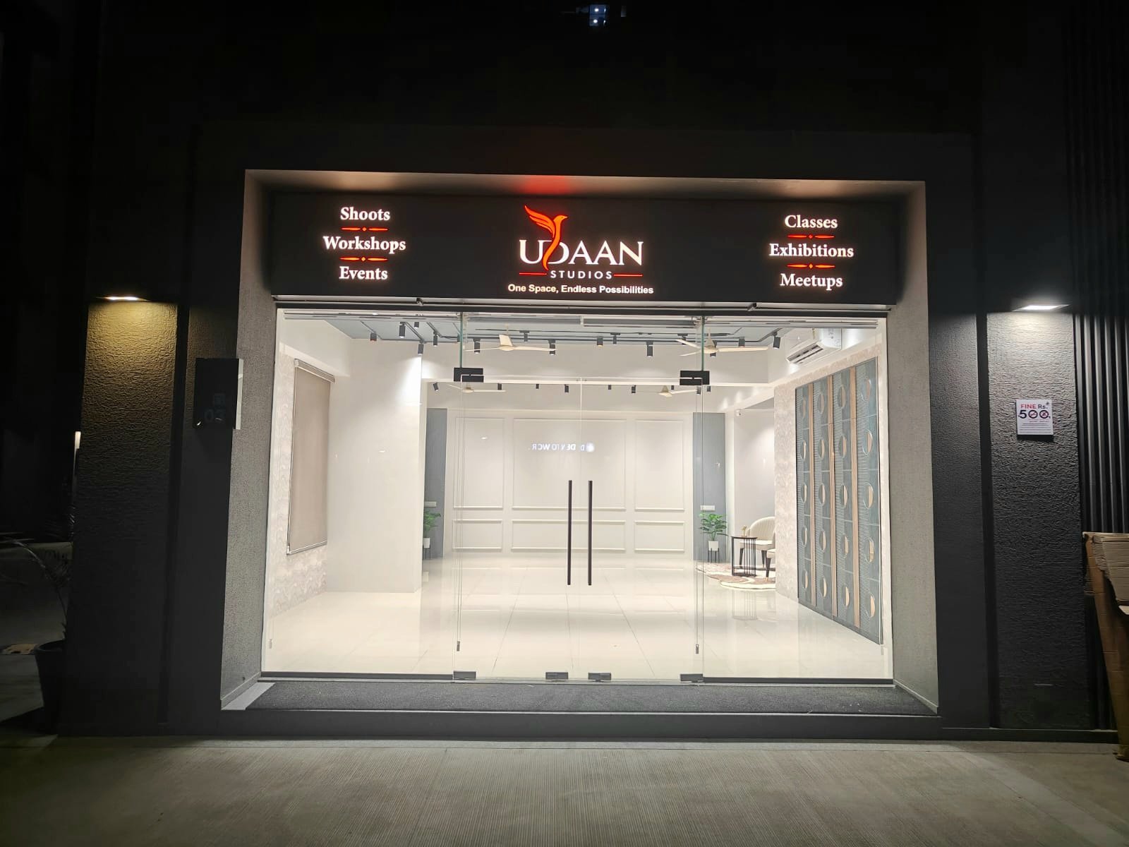 The glass frontage of Udaan Studios lit up at night